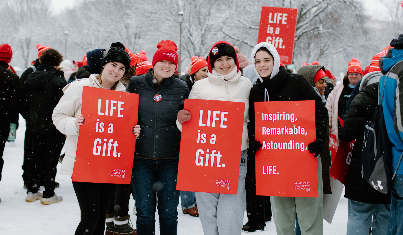 student smiles and holds pro life sign at the march for life